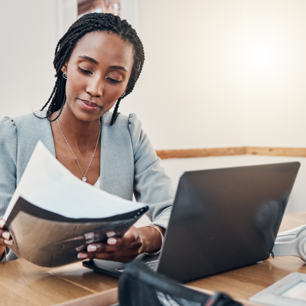 Businesswoman at office desk with laptop and paperwork.