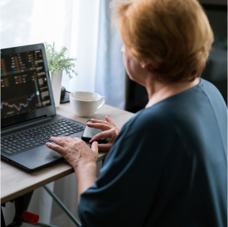 A client reading about market fluctuations on her laptop considers how her Return of Premium may help hedge against volatility.