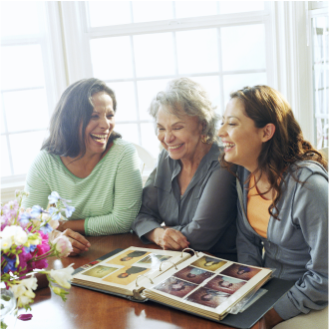 A woman and her adult daughters looking at a family photo album knowing they have an estate plan in place