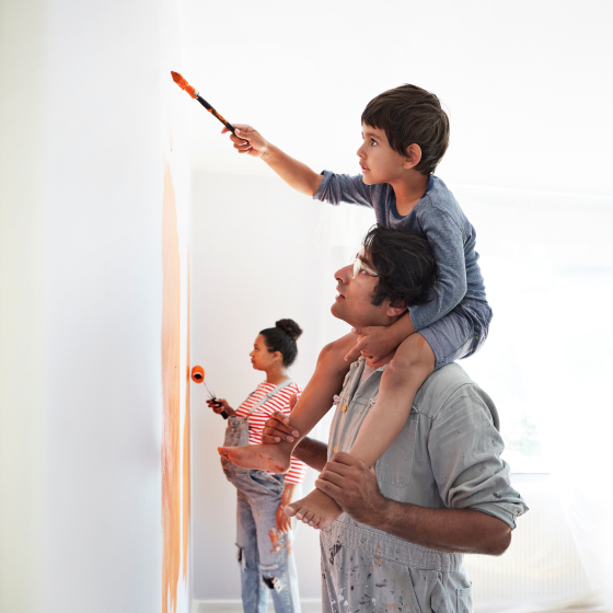A couple and their young son painting a baby's room