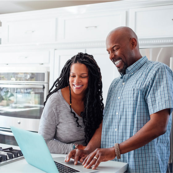 Couple in their kitchen exploring optional benefits on a laptop.