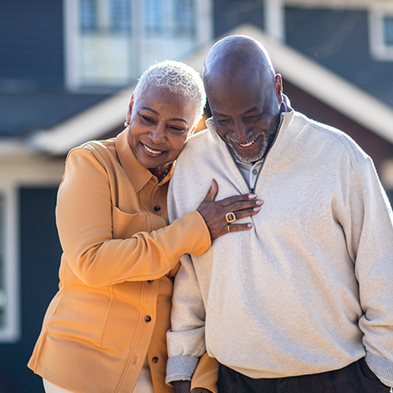 A happy couple walking closely together outside.
