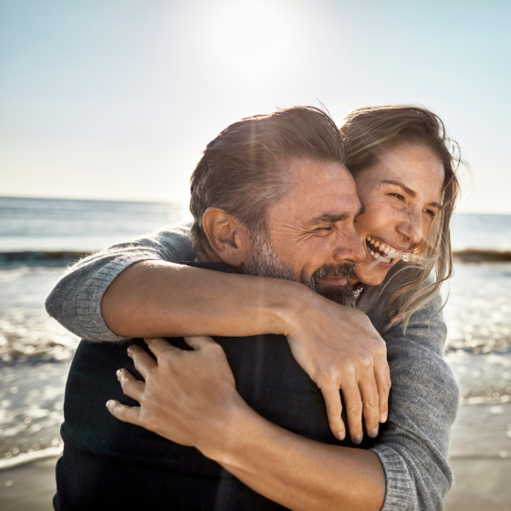Couple laughing on a beach feeling good about their retirement.