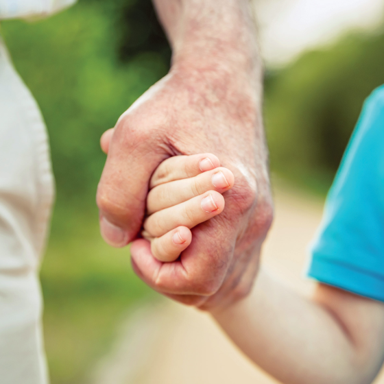 Parent protecting a child by holding his hand, much like an enhanced death benefit on a Protective annuity will protect his future.