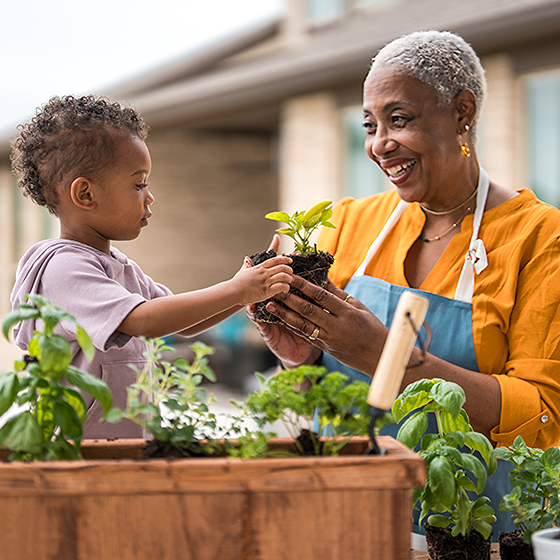 A middle aged woman smiling in front of her grandchild knowing her retirement goals are protected.