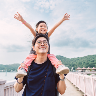 A father holding his young daughter and smiling, knowing they are protected with term life insurance
