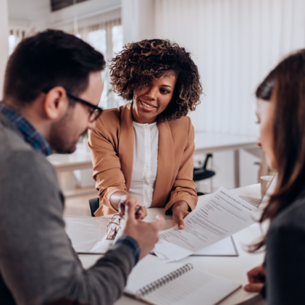 A financial professional reviews protection needs with her clients, a man and a woman.