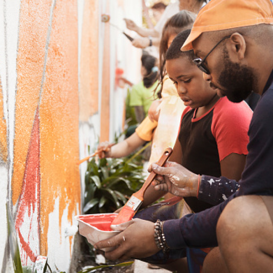 A family helping to paint a mural as a community project supported with charitable giving
